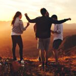 Joyful group of young adults enjoying a sunset view in a mountainous landscape in Brazil.
